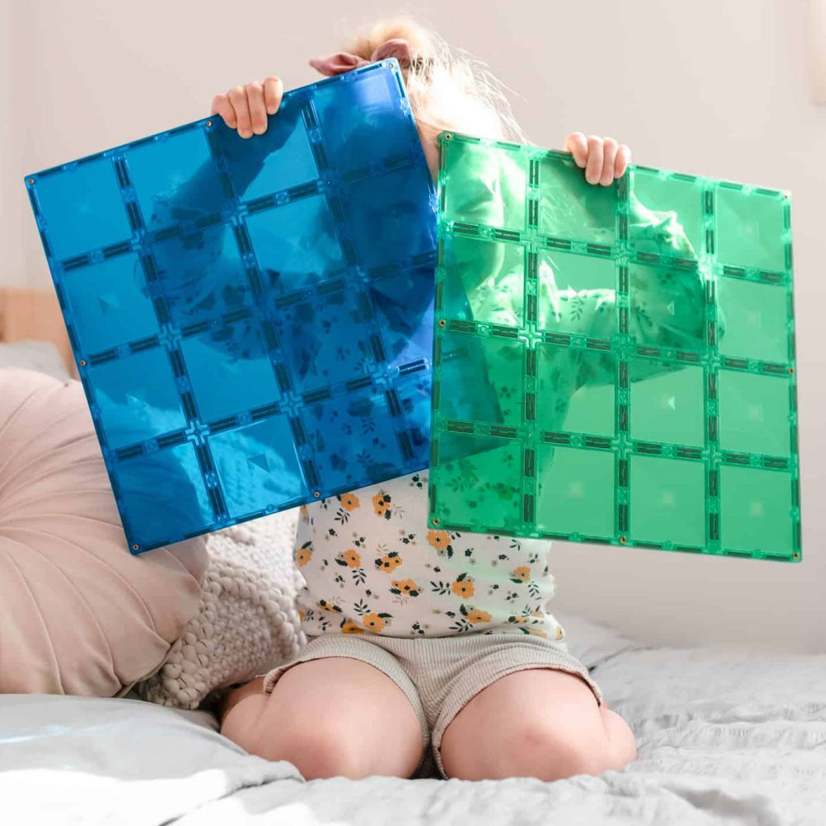 Child holding Connetix Blue & Green Base Plates