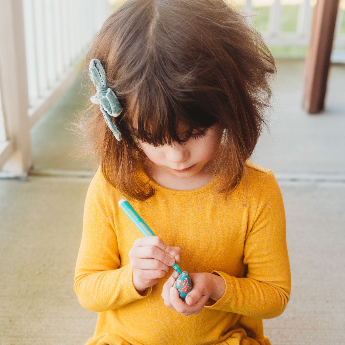 The Pencil Grip Co Magic Stix Washable Acrylic Markers child drawing on a small rock.
