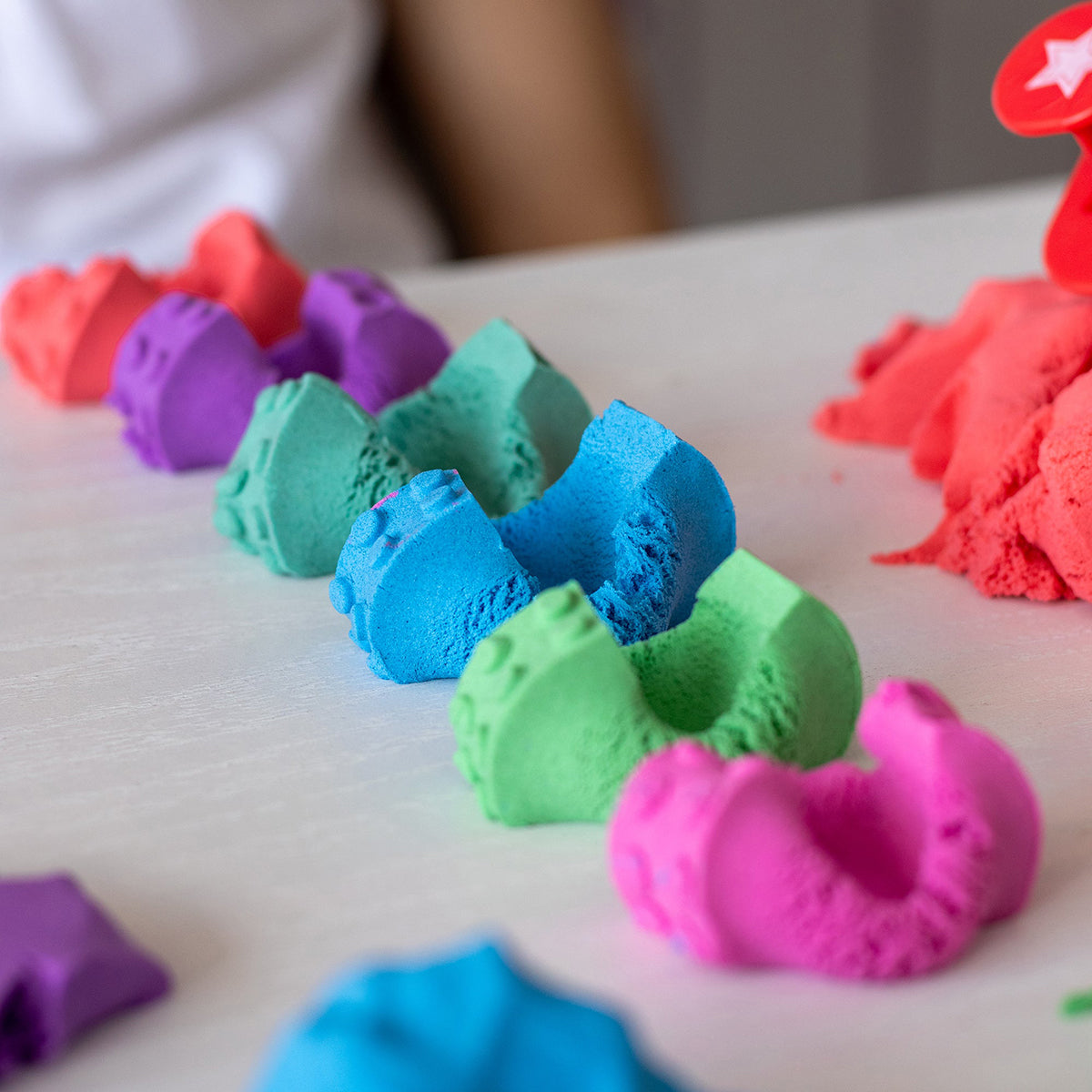 Child playing with many colors of Mad Mattr sensory dough.