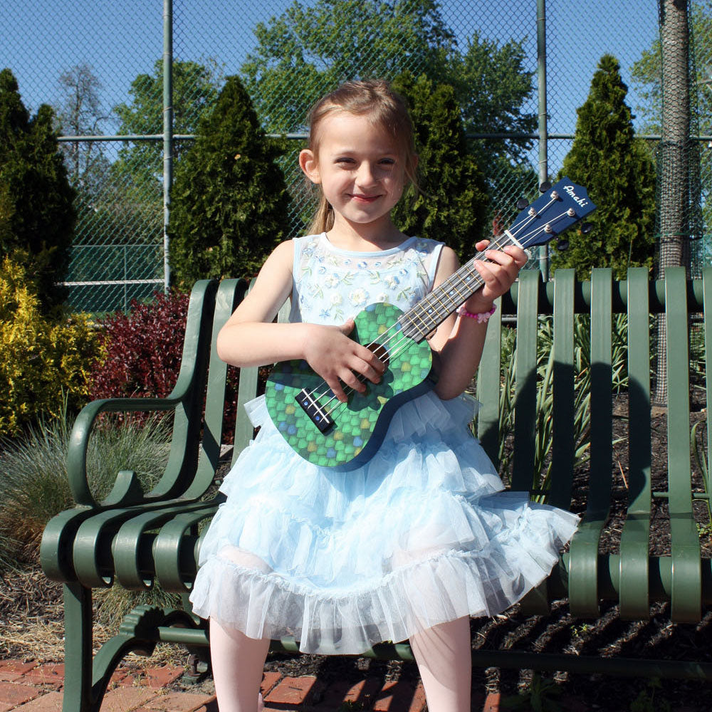 Child playing the Amahi Dragon Scale Painted Soprano Ukulele