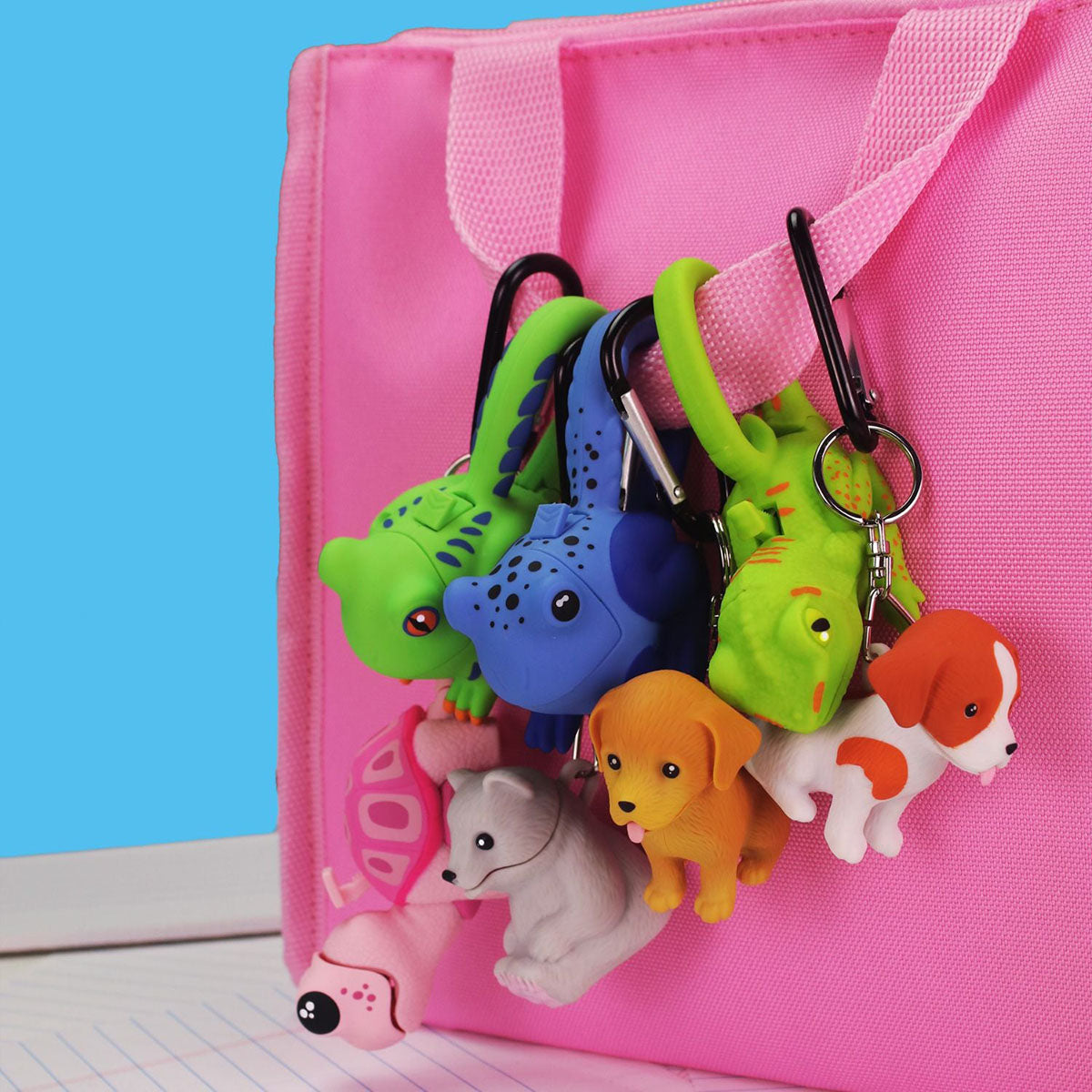 An assortment of Big Discoveries Wildlights LED Carabiner Animal & Dinosaur Lights clipped to a pink bag handle