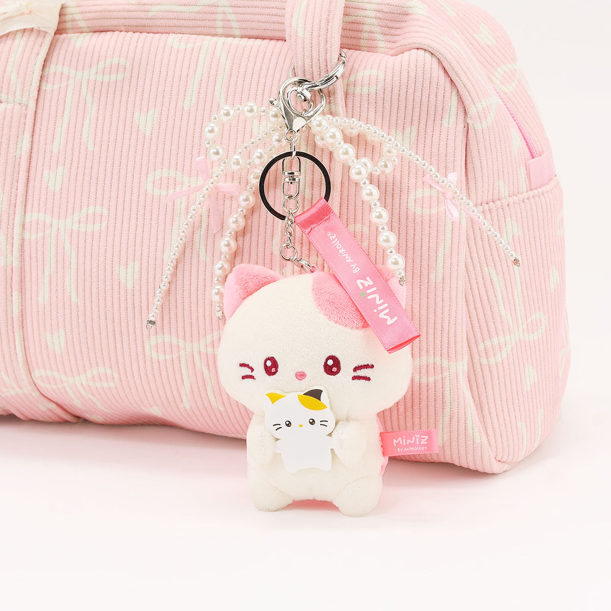 Coosy Anirollz Miniz Mini-Me Kittiroll clipped to a bag.