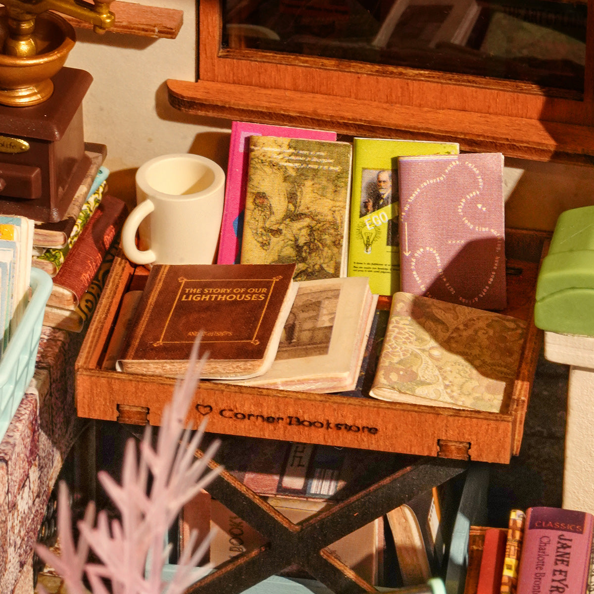 Closeup of a miniature tray of books inside the Corner Bookstore DIY Miniature House Kit from Hands Craft.