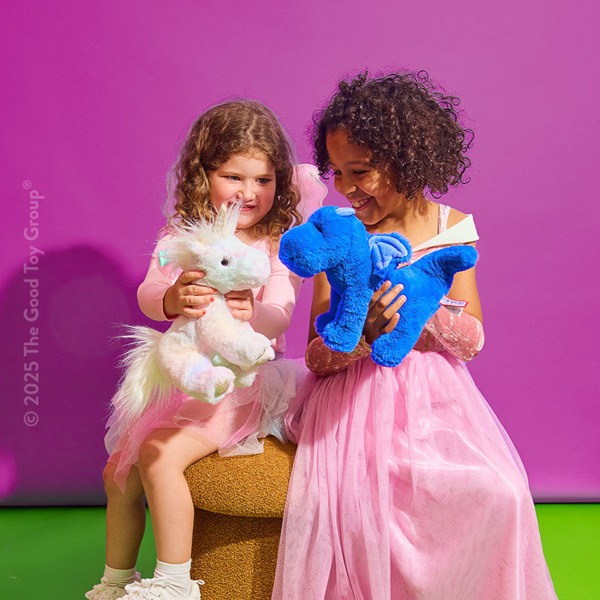 Two children playing with Douglas Cuddle Toys' Indie Blue Dragon and Kylie Unicorn