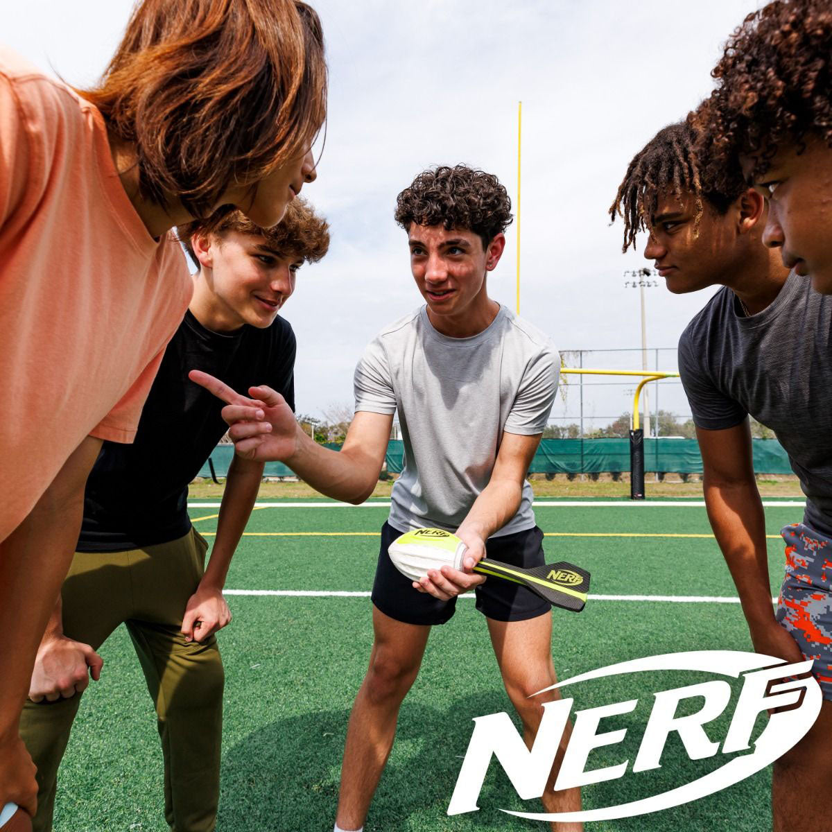 A group of kids in a huddle, getting ready to play with the Nerf Vortex Lightstrike Football.