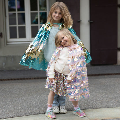Children wearing the Great Pretenders 5th Avenue Paillette Capes in Pink and Mermalicious (Aqua-blue and Gold)