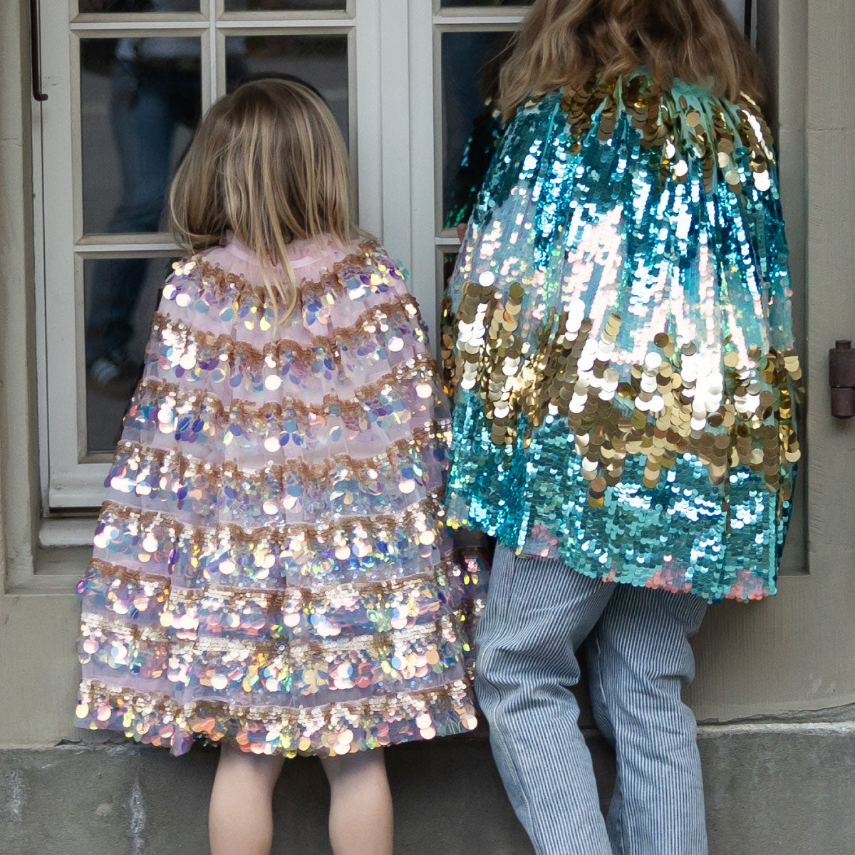 Children wearing the Great Pretenders 5th Avenue Paillette Capes in Pink and Mermalicious (Aqua-blue and Gold)