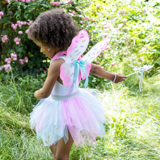 Child wearing Great Pretenders Think Mint Pink Skirt, Wings, and Wand Set fairy costume with tutu, wings, and wand.