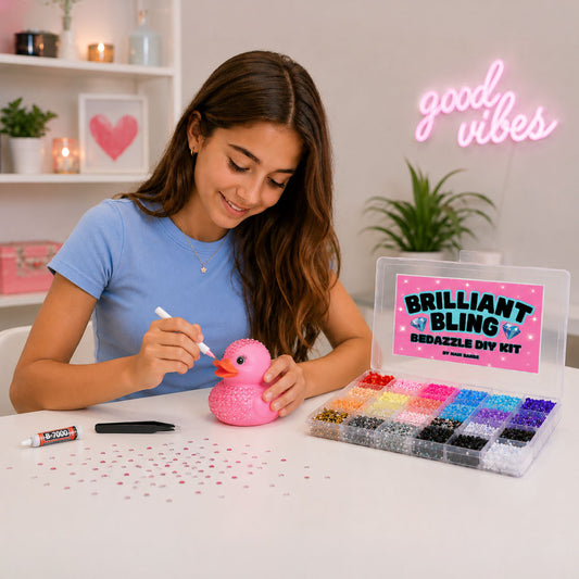 A teen girl sits at a white table, customizing a pink rubber duck with gemstones from the Brilliant Bling Bedazzle Kit. 