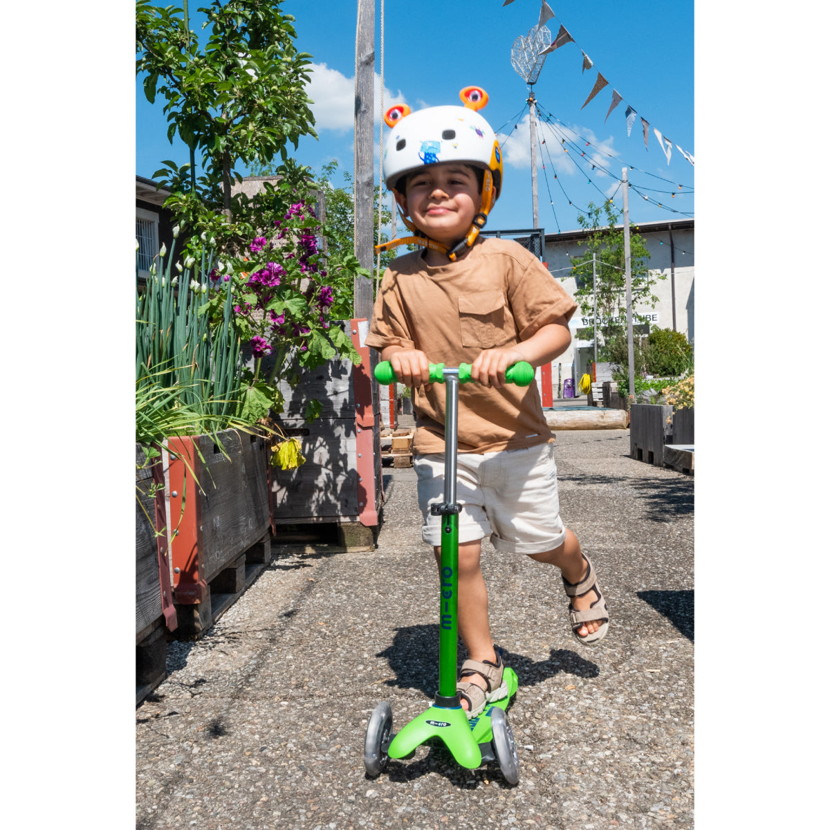 Child riding a Micro Kickboard Mini Deluxe Scooter LED Wheels - Green & Blue