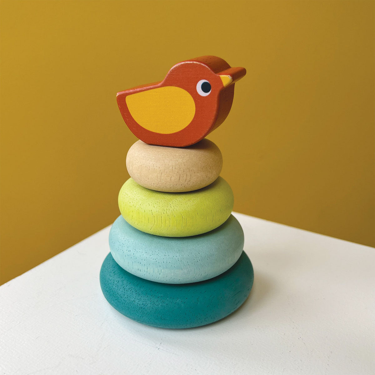 Wooden, cute and colorful stacking toy with four donut-shaped rings of different sizes and a cute bird perched on top, from Mentari.